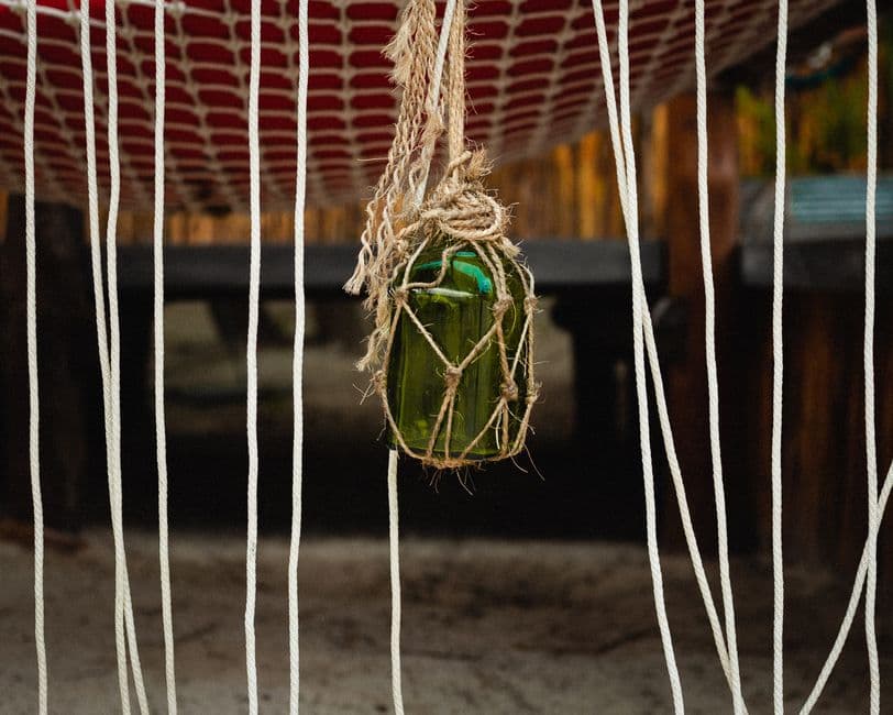 A glass bottle hanging outdoors against a rustic backdrop