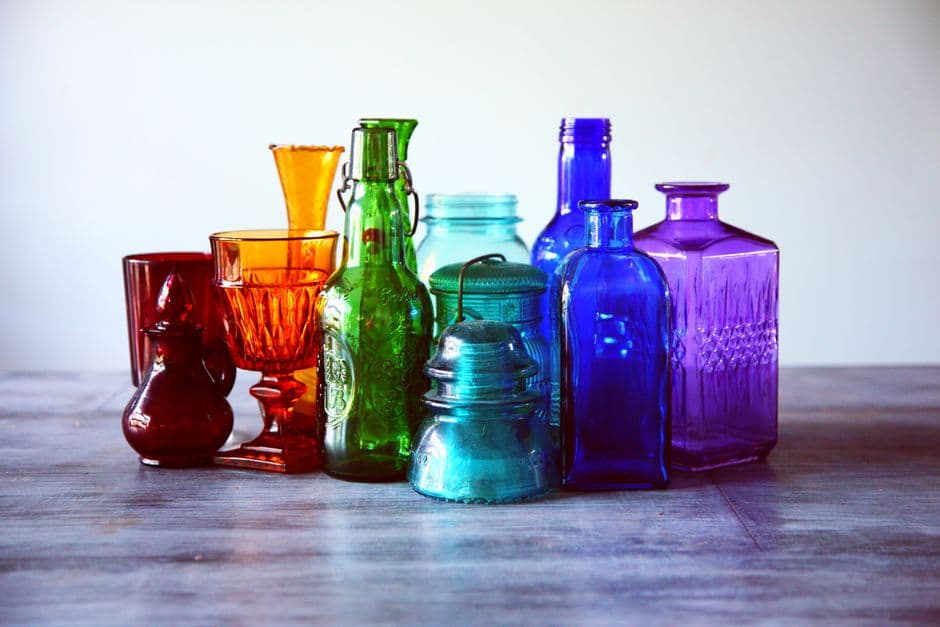 An array of colorful vintage glass bottles on a wooden table