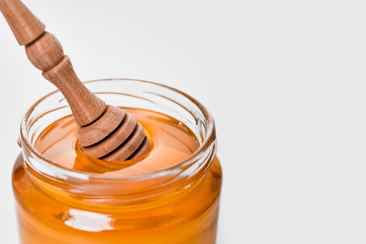 A jar of honey with a wooden dipper